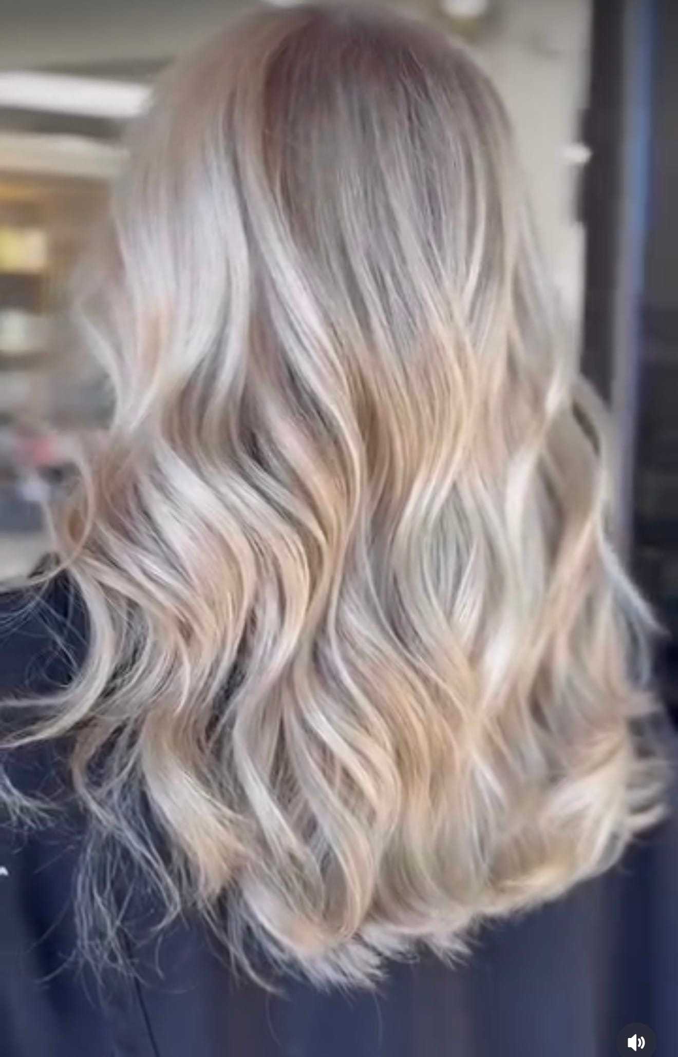 Wavy blonde hair with highlights cascading down the back in soft waves.